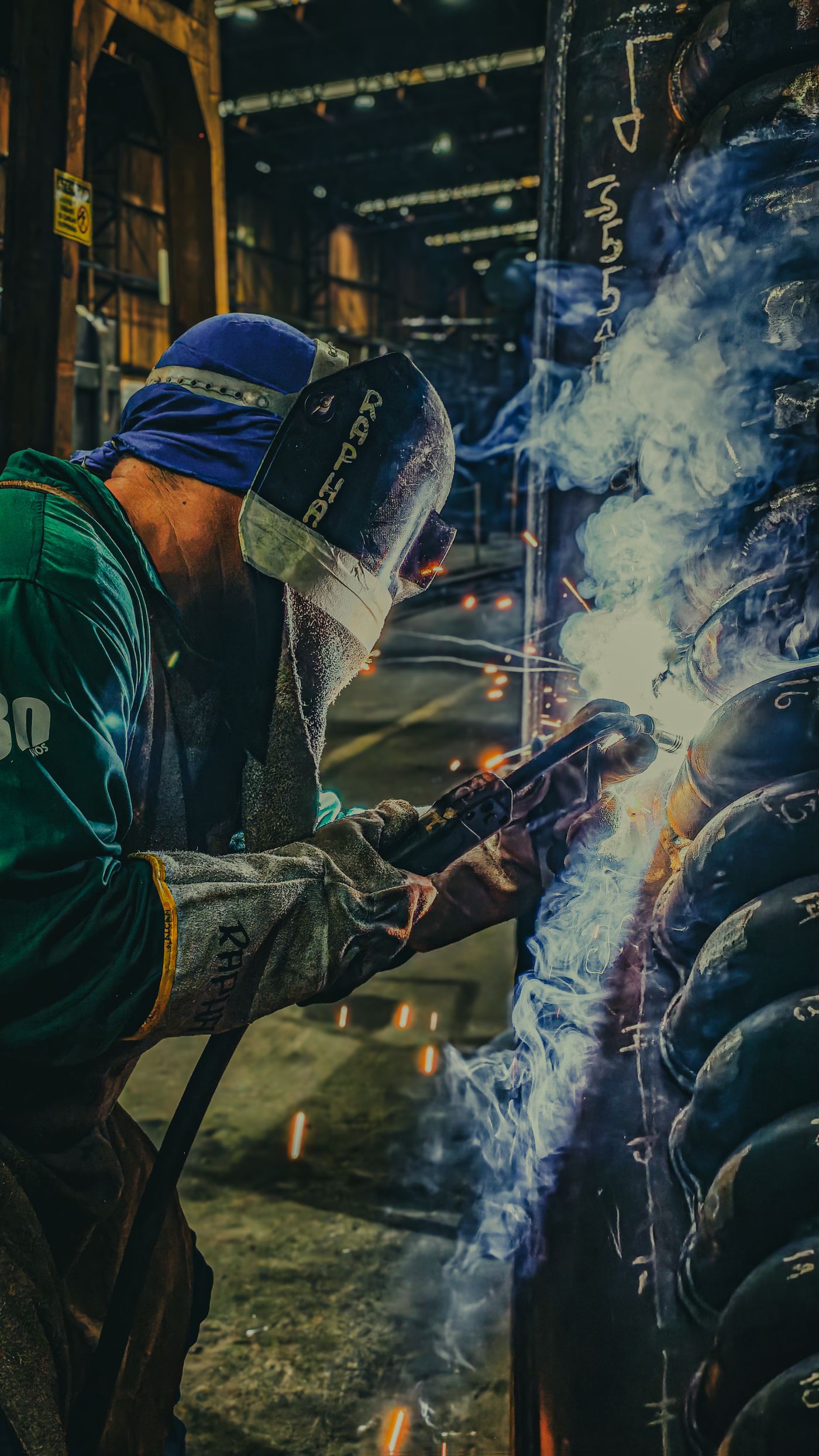 Welder fabricating a steel component in a metalworking shop